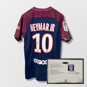 May include: A navy blue Neymar Jr. football shirt with the number 10 in white, and a signature. The shirt has burgundy sleeves and collar. A framed certificate of authenticity is displayed.