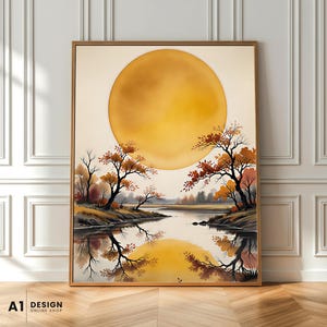 May include: A framed wall art print featuring a large, golden-yellow sun centered above a calm river landscape. The scene includes dark, silhouetted trees with orange and brown autumn foliage along the banks, with their reflections visible in the water.