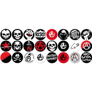 Puede incluir: Una colección de botones redondos en blanco y negro con varios símbolos anarquistas. Los diseños incluyen calaveras, el símbolo de la anarquía, un puño y las palabras "RESIST" y "DESTROY AUTHORITY". Algunos botones tienen detalles en rojo.