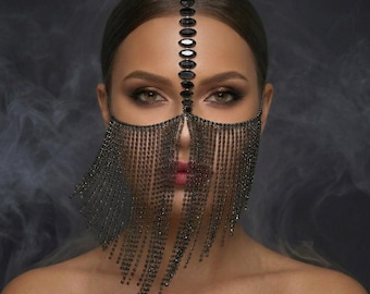 May include: A black crystal face mask featuring a vertical row of oval-shaped stones extending from the forehead to the bridge of the nose, with multiple strands of shimmering black crystals draping downwards to cover the lower half of the face.