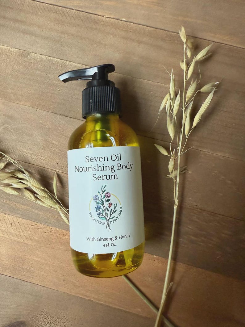 May include: A clear plastic bottle with a black pump dispenser containing a golden yellow body serum. The white label reads Seven Oil Nourishing Body Serum, With Ginseng & Honey, 4 Fl. Oz., and features a small illustration of wildflowers.