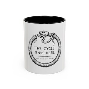 May include: A white ceramic mug with a black interior and rim. The exterior features a black ink-style illustration of an Ouroboros snake eating its own tail. Centered text reads: The cycle ends here. Below is the Latin phrase: Omnia fluunt, omnia redeunt.