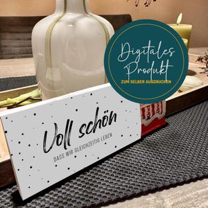 Può includere: Un cartello rettangolare bianco con le parole "Voll schön" in corsivo nero e la frase "DASS WIR GLEICHZEITIG LEBEN" sotto. Il cartello è decorato con puntini neri. È visibile anche un cerchio turchese con la scritta bianca "Digitales Produkt ZUM SELBER AUSDRUCKEN".