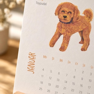 May include: A desk calendar page for January featuring a brown toy poodle illustration, the name Milo, and the text Toypudel. The calendar grid displays days of the week abbreviated as Mo, Di, Mi, Do, Fr, Sa, So, with dates from 1 to 31 printed in black.