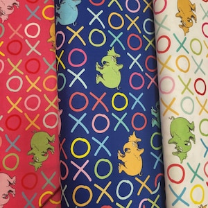 May include: Three fabric swatches with colorful patterns. One is red with pink characters and colorful XOXO symbols. Another is blue with green, blue, and yellow characters and XOXO symbols. The last is white with green and yellow characters and XOXO symbols.