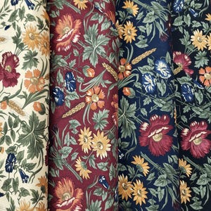 May include: Four rolls of fabric with floral patterns. The designs showcase flowers in red, orange, yellow, and blue, accompanied by green leaves and wheat. The backgrounds are cream, burgundy, navy, and black.