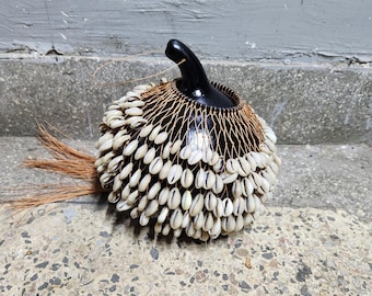 タカラガイの殻でできたひょうたんのシェケレ：白いビーズで飾られた