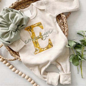 Macacão de bebê personalizado com estampa floral vintage e letras, ideal para a saída da maternidade.