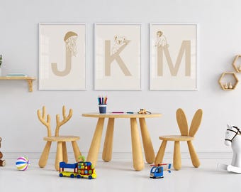 Puede incluir: Un área de juegos infantil con una mesa redonda de madera de cuatro patas, dos sillas de madera con respaldos en forma de orejas de animal, tres cuadros de pared con las letras J, K y M con ilustraciones de animales y varios juguetes.