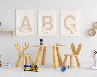 Puede incluir: Un área de juegos infantil con una mesa redonda de madera y dos sillas, una con respaldo de astas de ciervo y otra con orejas de conejo. Tres láminas de pared enmarcadas muestran las letras A, B y C con ilustraciones de animales.