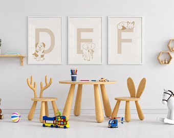 Puede incluir: Tres cuadros de pared con las letras D, E y F junto a ilustraciones de un perro, un elefante y un zorro. El conjunto incluye una mesa redonda de madera, dos sillas con respaldos en forma de orejas, un oso de peluche, un tren y un caballito.