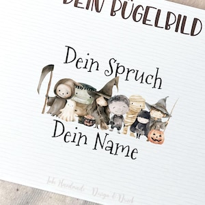 Op de afbeelding: Een platte lay-out met een beige baby-outfit, een kaart met de tekst "DEIN BÜGELBILD" en een cartoonillustratie, en houten knopen. De kaart bevat ook instructies in het Duits. De outfit heeft drie knopen.