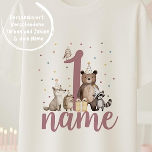 Könnte beinhalten: Weißes T-Shirt mit einem Design für den ersten Geburtstag. Das Design zeigt die Zahl "1", Waldtiere und das Wort "name" in Malve. Das T-Shirt ist mit bunten Konfetti verziert.