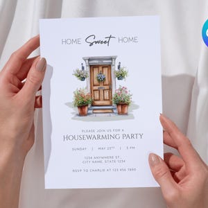 May include: A white invitation card held by hands, featuring the text "Home Sweet Home" above an illustration of a door with floral accents. The card is for a housewarming party, with date, time, and address details.