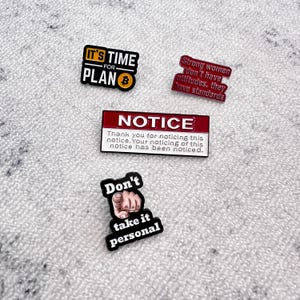 Könnte beinhalten: Vier Emaille-Anstecknadeln mit Text. Eine Anstecknadel sagt "IT'S TIME FOR PLAN" mit einem Bitcoin-Symbol. Eine andere sagt "Strong women don't have attitudes, they have standards." Eine dritte sagt "NOTICE". Die letzte sagt "Don't take it personal."