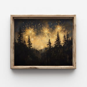 Op de afbeelding: Een ingelijste kunstdruk met een vuurwerkshow boven een bos. Het kunstwerk toont gouden vuurwerk dat in de nachthemel boven silhouetten van groenblijvende bomen barst. Het frame is gemaakt van lichtgekleurd hout.