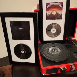 Two framed vintage Metallica Master of Puppets / Black Album CDs and Inserts.