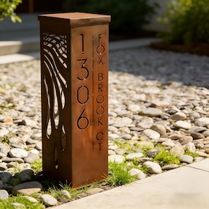 Puede incluir: Un letrero de dirección rectangular de metal oxidado con los números "1306" y el texto "FOX BROOK CT" recortados. El letrero tiene un patrón decorativo en forma de ola en el lado izquierdo.