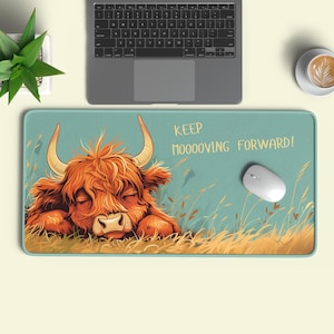 Könnte beinhalten: Rechteckiges Mauspad mit türkisblauem Hintergrund. Es zeigt eine Illustration einer braunen Highland-Kuh mit großen Hörnern, die in einem Grasfeld liegt. Der Text "KEEP MOOOOVING FORWARD!" ist rechts aufgedruckt.