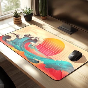 Puede incluir: Alfombrilla de ratón rectangular con una vibrante ilustración de una ola y un sol poniente. El diseño incorpora tonos de rojo, azul y amarillo. Un ratón inalámbrico negro está en el lado derecho de la alfombrilla. La alfombrilla está sobre un escritorio de madera.