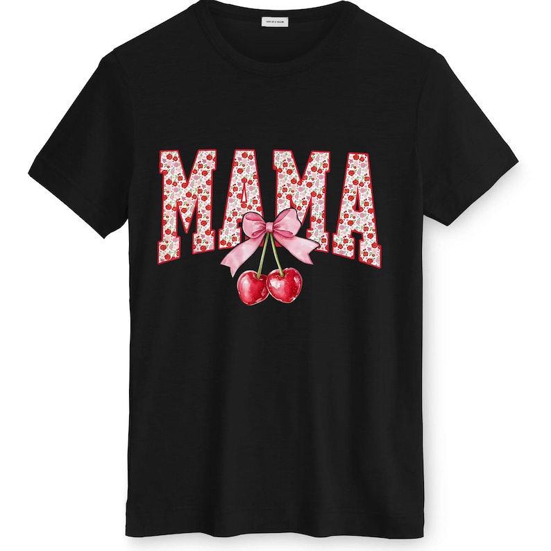 May include: Black t-shirt featuring the word "MAMA" in a red and white floral design. A pink bow and two red cherries are below the word. The shirt has a crew neck.