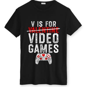 May include: Black t-shirt with white distressed text that reads "V IS FOR VIDEO GAMES." The word "VALENTINE" is crossed out in red. A white controller graphic with red hearts is at the bottom.