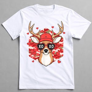 May include: White t-shirt featuring a cartoon deer wearing heart-shaped sunglasses with "XO" on the lenses and a red hat. The deer is set against a red and white camouflage background, with red hearts scattered around.