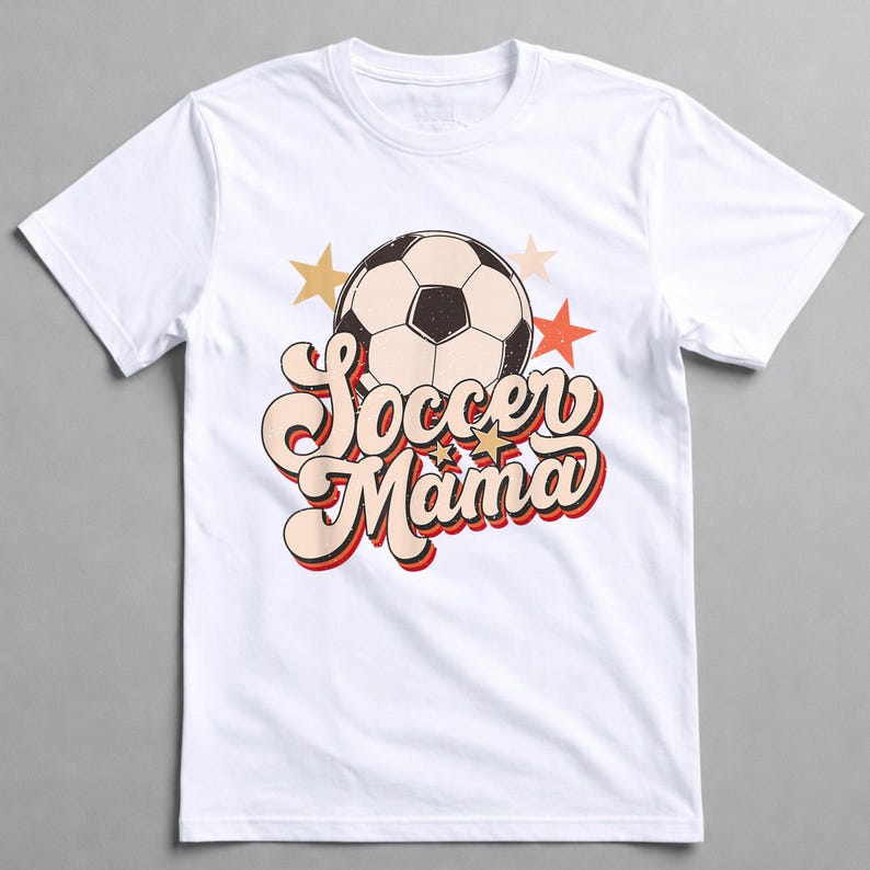 May include: White t-shirt featuring a soccer ball graphic and the text "Soccer Mama" in a retro font. The design includes gold and red stars. A casual, comfortable tee for soccer enthusiasts.