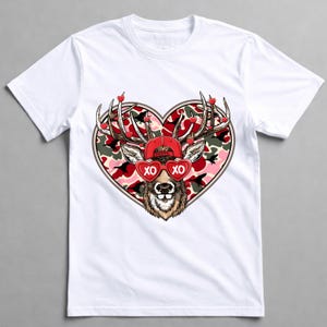 May include: White t-shirt featuring a deer graphic with a red cap and heart-shaped sunglasses that read "XO." The deer is set against a heart-shaped camouflage background, with small red hearts on the antlers. A fun and festive design.