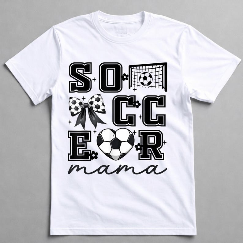 May include: White t-shirt with a black and white soccer-themed graphic. The design includes the word "SOCCER" with a soccer ball bow, a soccer net, and a heart-shaped soccer ball. The word "mama" is written in cursive.