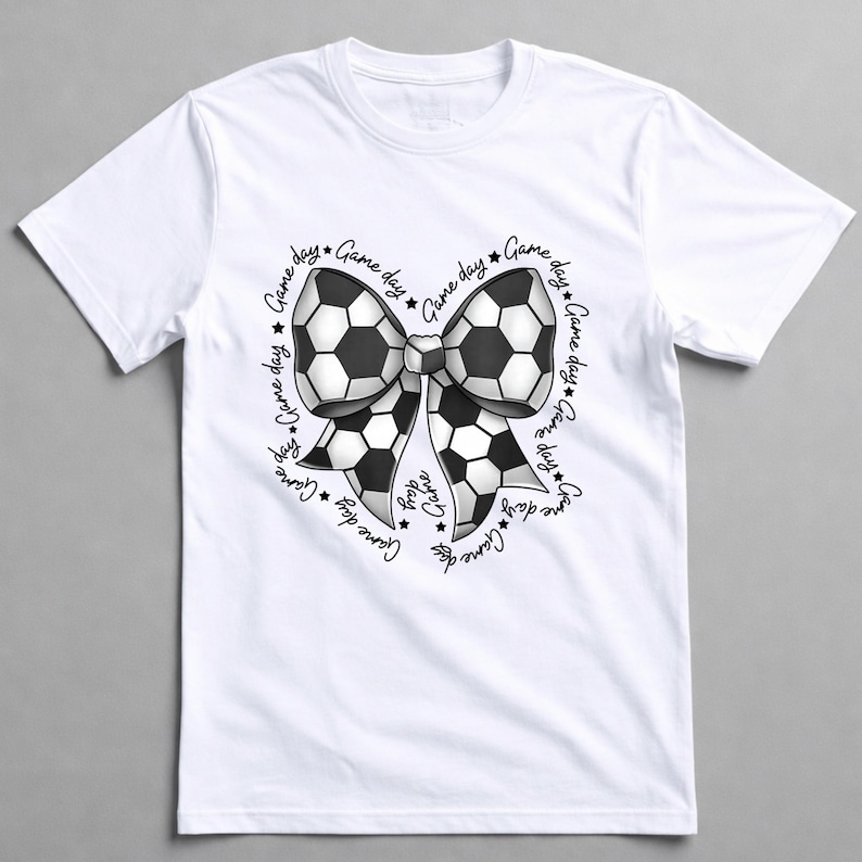 May include: White t-shirt featuring a soccer ball bow design. The bow is black and white, with the words "Game Day" and stars encircling the bow. A casual tee for soccer fans.