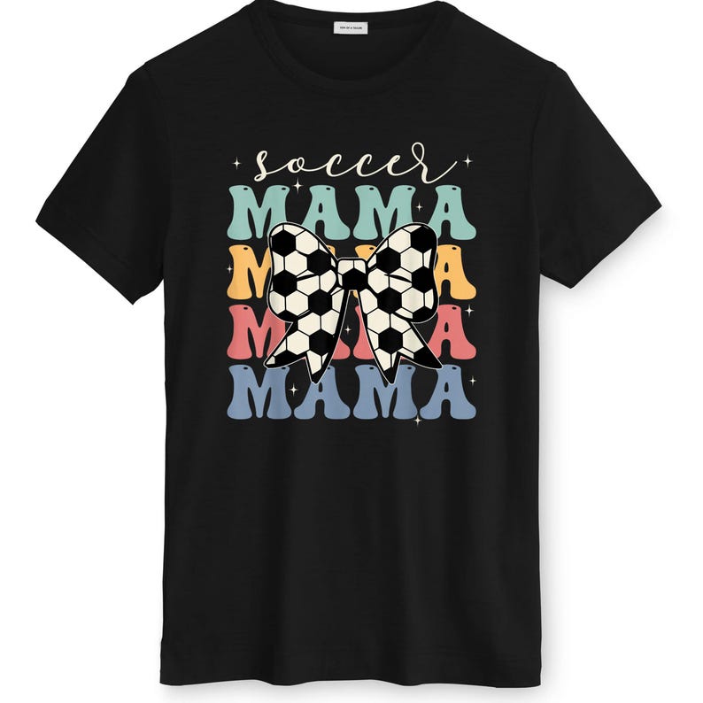 May include: Black t-shirt with a colorful graphic design. The design features the words "soccer mama" in a retro font, with a soccer ball bow in the center. The text is layered in blue, orange, pink, and teal.
