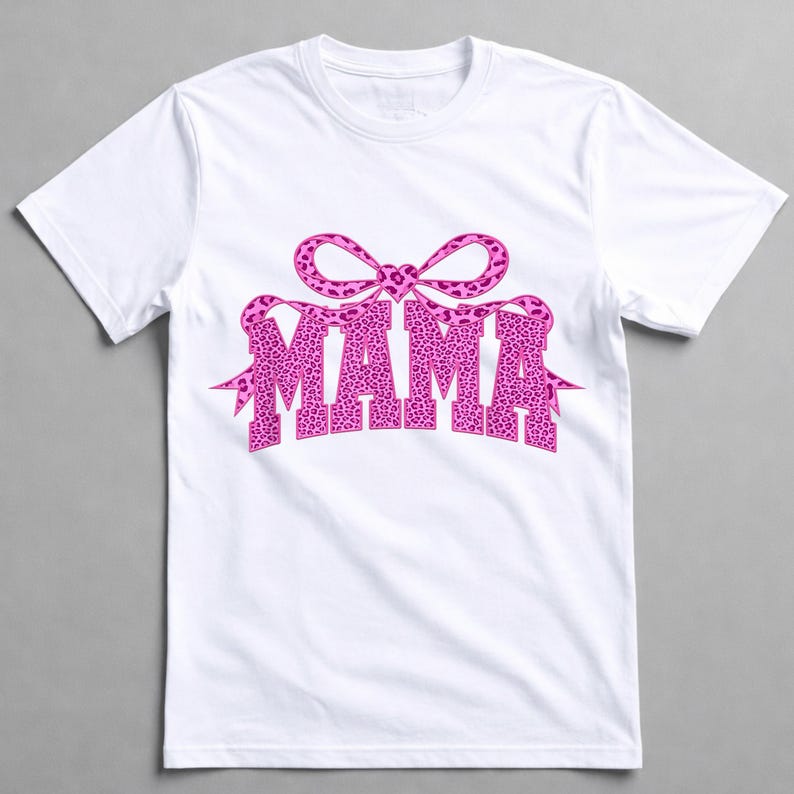 May include: White t-shirt with the word "MAMA" in a pink leopard print font, and a matching bow design. The t-shirt has a crew neck, suitable for everyday wear.