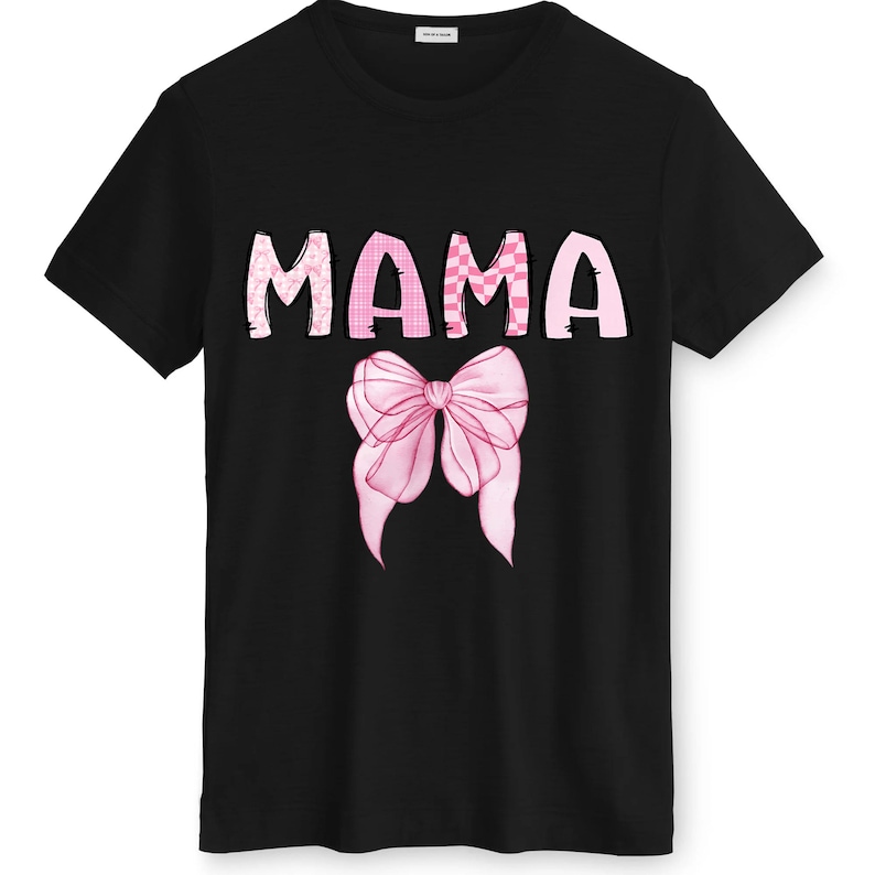 May include: Black t-shirt featuring the word "MAMA" in pink, patterned letters. A pink bow graphic is centered below the word. The shirt has a crew neck and short sleeves.
