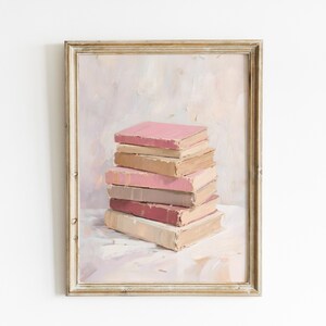 May include: A framed painting of a stack of books. The books have pink, beige, and brown covers. The painting has a soft, pastel color palette and a vintage aesthetic. The frame is a light gold color.