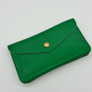 May include: A bright green wallet with a textured surface. The wallet has a flap closure secured by a gold-colored button. The wallet is rectangular and appears to be made of leather.