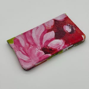 May include: A rectangular case with a floral design. The case features a vibrant painting of pink flowers against a red background. The edges of the case are green and the overall design is artistic.