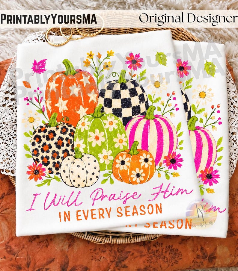 May include: A white t-shirt featuring a graphic of six pumpkins with various patterns including stars, leopard print, checkers, stripes, and flowers, surrounded by colorful floral accents. The text reads, I Will Praise Him IN EVERY SEASON.