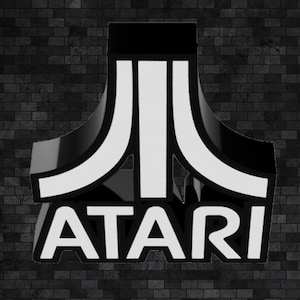 May include: Black and white Atari logo against a dark brick wall background. The logo features a stylized design with the word "ATARI" in white, bold lettering. The overall aesthetic is retro and evokes a sense of classic gaming.