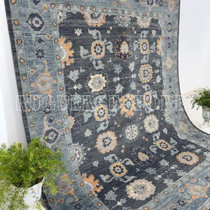 Könnte beinhalten: Ein großer, rechteckiger Teppich in Dunkelgrau und Türkis. Der Teppich hat ein aufwendiges Blumenmuster in Gelb, Grau und Türkis. Der Rand ist ein helleres Türkis mit sich wiederholenden geometrischen Mustern. Der Text "RUGERS STORE" ist sichtbar.