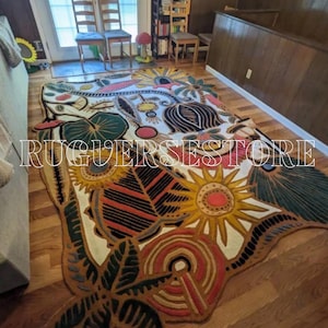 Può includere: Un grande tappeto colorato con un design botanico con girasoli, foglie e altri elementi floreali. Il tappeto ha un bordo marrone e uno sfondo color crema. Il testo "RUGVERSESSTORE" è sul tappeto.