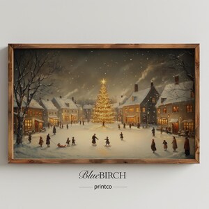 May include: A framed print of a winter village scene at night. A large, illuminated Christmas tree stands in the center of the town square, surrounded by snow-covered buildings and figures. The artwork is signed "BlueBIRCH printco."