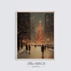 May include: A framed print of a winter scene featuring a large, illuminated Christmas tree in a city park. Silhouetted figures walk along a path, with tall buildings in the background. The print has a warm, inviting color palette and the text "Blue Birch printco" at the bottom.