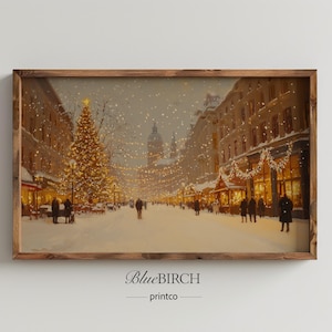 May include: A framed print of a winter scene. The artwork depicts a snowy street lined with buildings and a large Christmas tree. The buildings have lit windows and are decorated with garlands. The sky is filled with falling snow.