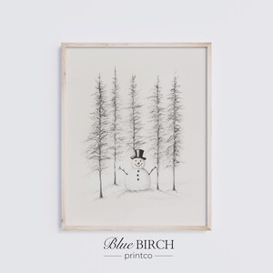 Può includere: Una stampa in bianco e nero incorniciata con un pupazzo di neve in una foresta. Il pupazzo di neve ha un cappello a cilindro e braccia di legno. La stampa è etichettata "Blue Birch printco" in basso.