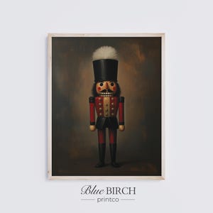 May include: A framed print of a traditional nutcracker figure. The nutcracker wears a red jacket, black trousers, and a tall black hat with a white plume. The background is a dark, textured brown. The text "Blue BIRCH printco" is at the bottom.