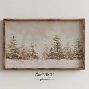 Op de afbeelding: Een ingelijste print met een winterlandschap met sneeuw en verlichte dennenbomen. Het kunstwerk heeft een zacht, gedempt kleurenpalet en een bruine houten lijst. De tekst "BlueBIRCH printco" staat onderaan.