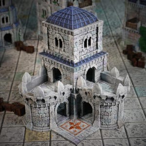 Peut inclure: Un château miniature en pierre avec un toit en tuiles bleues et des fenêtres cintrées. Le château possède deux tours rondes avec des créneaux et une façade texturée et détaillée. La base présente un motif de sol décoratif, suggérant un thème fantastique ou de jeu de société.