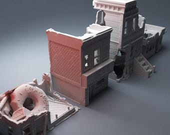 May include: A collection of miniature, distressed building models, including a donut shop, a brick-faced structure, and a multi-story building with stairs. The models are in shades of gray and pink, suggesting a post-apocalyptic or diorama theme.