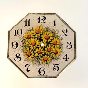 May include: Vintage octagonal clock face with a floral design. The clock face features a bouquet of yellow daisies with orange centers. Black numerals mark the hours against a cream-colored background. The clock face is marked "SPARTUS MADE IN U.S.A."
